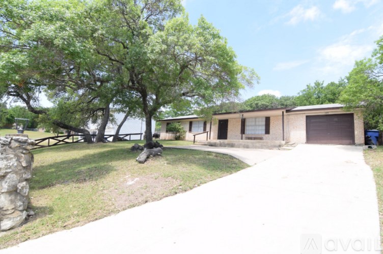 A tree in front of a building with a stone pillar on the left.