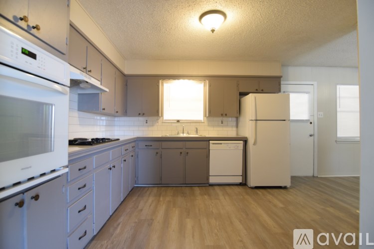 A kitchen with white appliances and wooden floors.