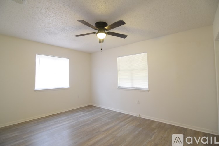 A room with a ceiling fan and two windows.