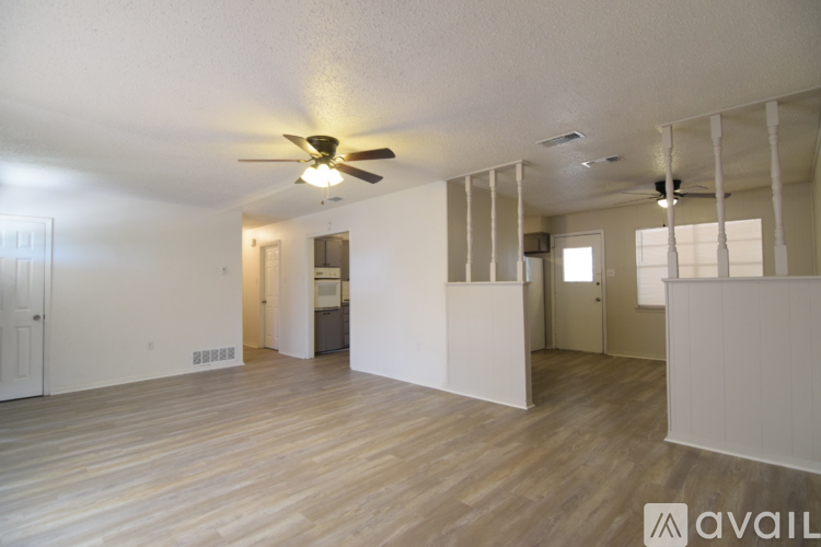 A spacious room with wooden floors and a ceiling fan.