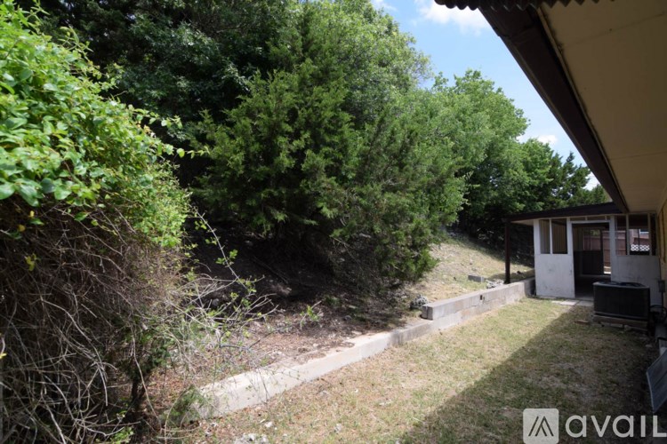 A backyard with a house, trees, and a small garden.