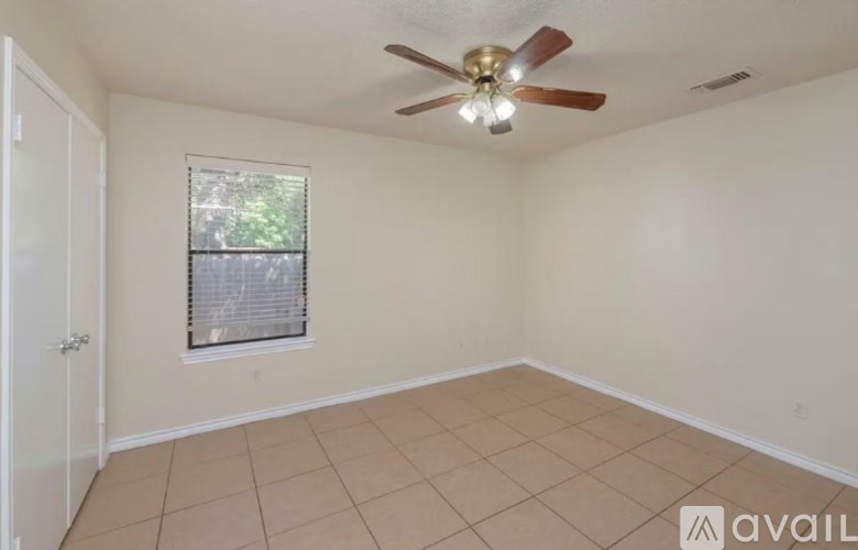 A room with a ceiling fan and a window with blinds.