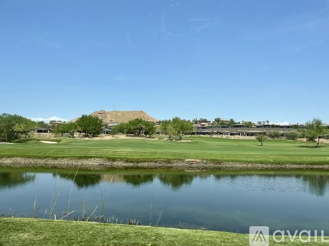 A golf course with a pond and trees in the background.