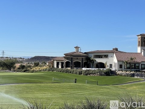 A large white building with a brown roof sits in the middle of a grassy field.