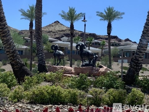 A statue of a bull is in the middle of a garden with palm trees.