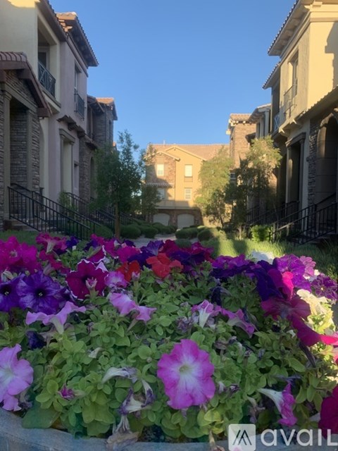 A flower bed with purple and white flowers in front of a row of houses.