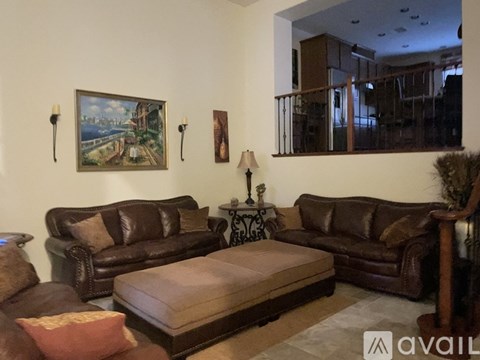 A living room with brown leather furniture and a painting on the wall.