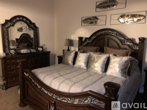 A bedroom with a large bed, a mirror, and a dresser.