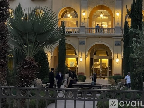 A group of people are standing outside a building with arched windows and a balcony.