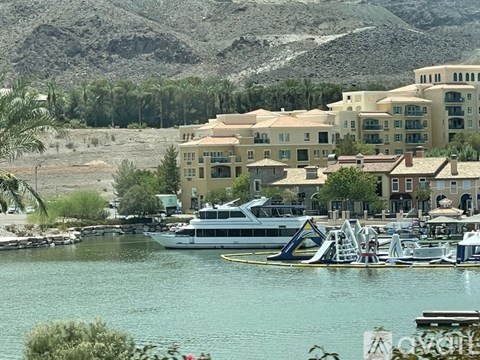 A large house is situated on the shore of a lake with a yacht in front of it.