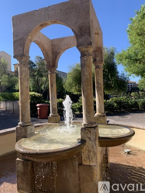 A stone fountain with a circular basin and a tall arched structure.