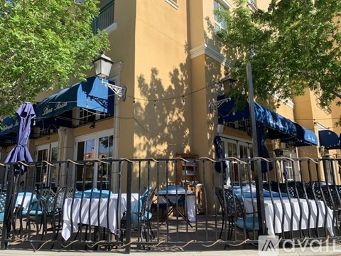 A restaurant with tables and chairs under blue umbrellas.