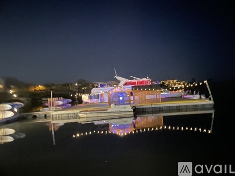 A nighttime view of a lit-up pier with a building and lights reflected in the water.