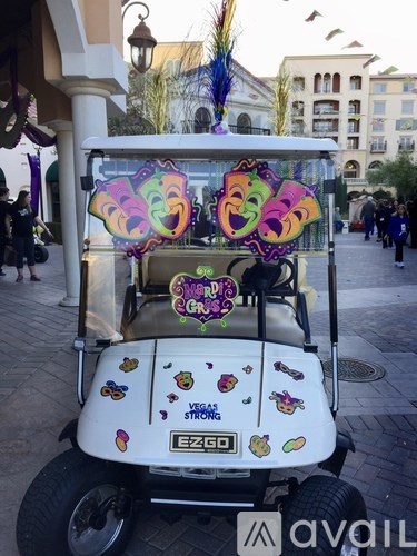 A white golf cart with a colorful design and the word "EZGO" on the side is parked on a street.