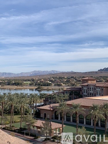 A large building with palm trees in front of it and mountains in the background.