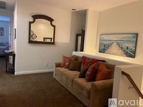 A living room with a couch and a painting of a bridge on the wall.