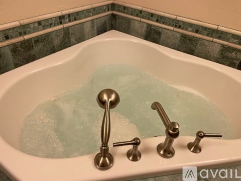 A white bathtub with a silver faucet and four handles.
