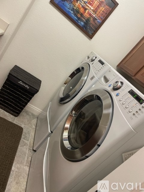 A front-loading washing machine with a control panel and a small black bag.