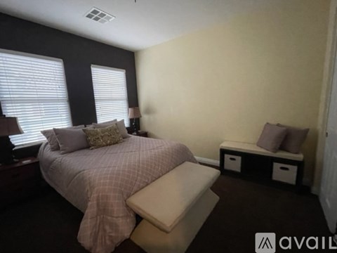 A bedroom with a bed, nightstand, and window with blinds.