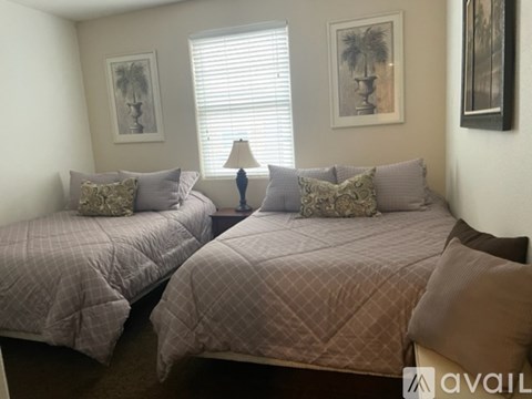 Two twin beds with pillows and a lamp on a bedside table.