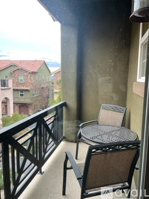 A balcony with a table and chairs overlooking a residential area.