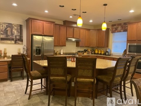 A kitchen with brown wooden cabinets and a large island with chairs around it.