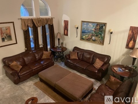 A living room with brown leather furniture and a painting on the wall.