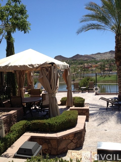 A gazebo is surrounded by a stone wall and a bench.