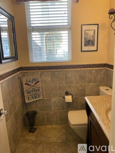 A bathroom with a tile wall and a toilet.