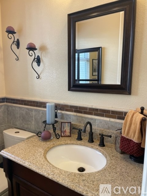 A bathroom with a toilet, a sink, a mirror, and a towel.