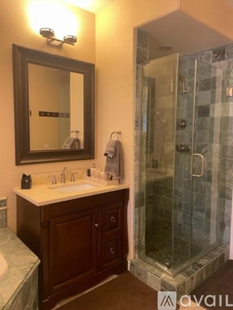 A bathroom with a sink, mirror, and shower.