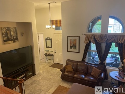 A living room with a brown leather couch and a television.