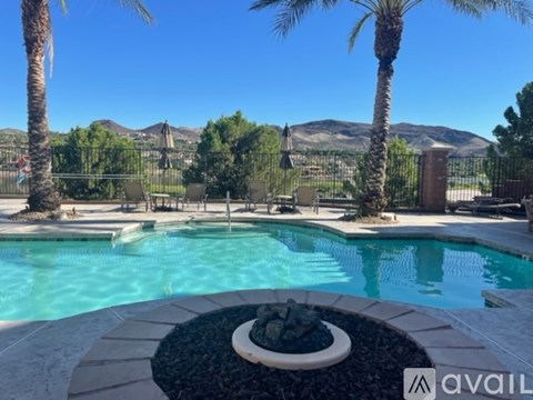 A pool surrounded by palm trees and a mountain in the background.