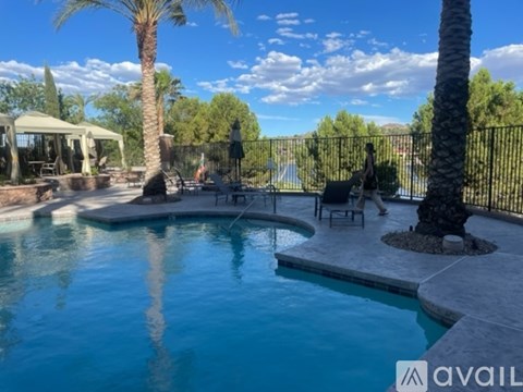 A pool surrounded by a black fence with a palm tree in the background.