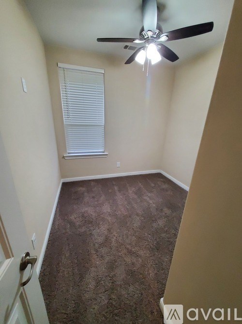 A room with a ceiling fan and a window with blinds.