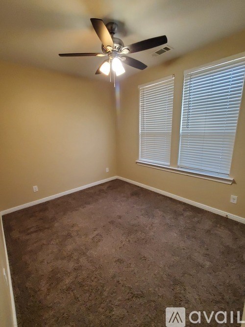 A room with a ceiling fan and carpeted floor.