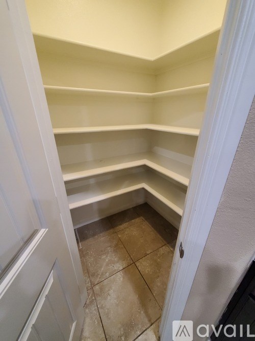 A white pantry with shelves and a tiled floor.