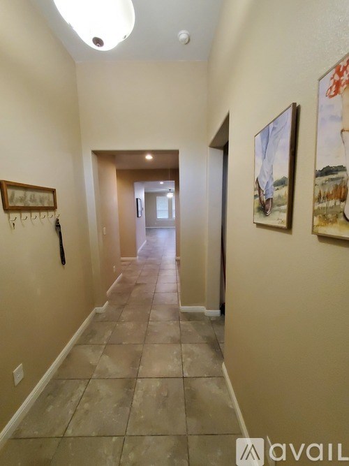 A hallway with a tiled floor and a painting on the wall.
