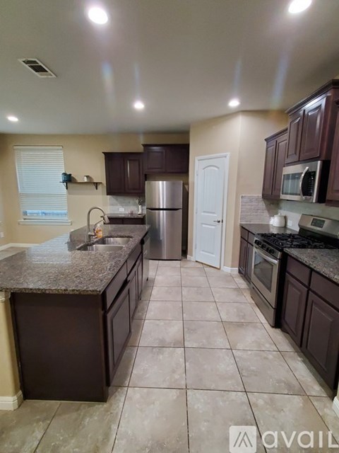 A kitchen with brown cabinets and a granite countertop.