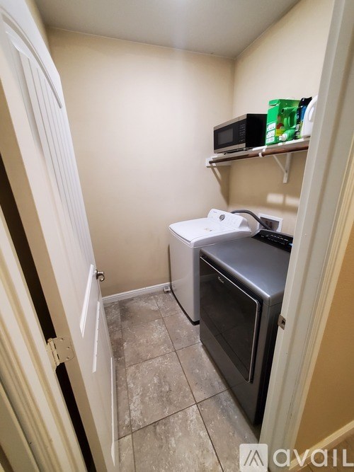 A small kitchen with a microwave, oven, and a shelf with a green cup on it.