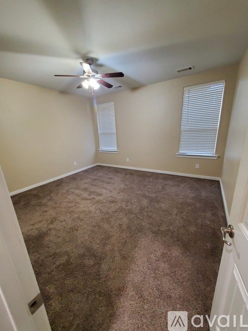 A room with a ceiling fan and carpeted floor.