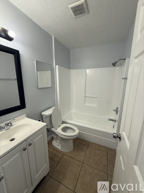 A bathroom with a toilet, sink, and mirror.