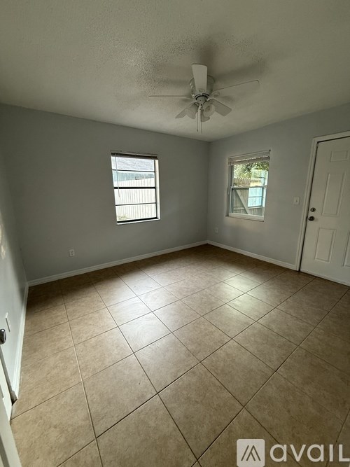 A room with a ceiling fan and two windows.