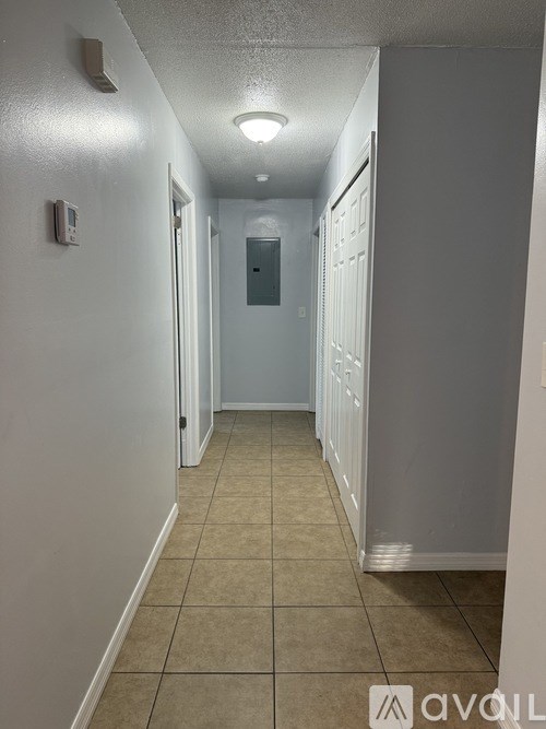 A long hallway with white walls and tiled flooring.