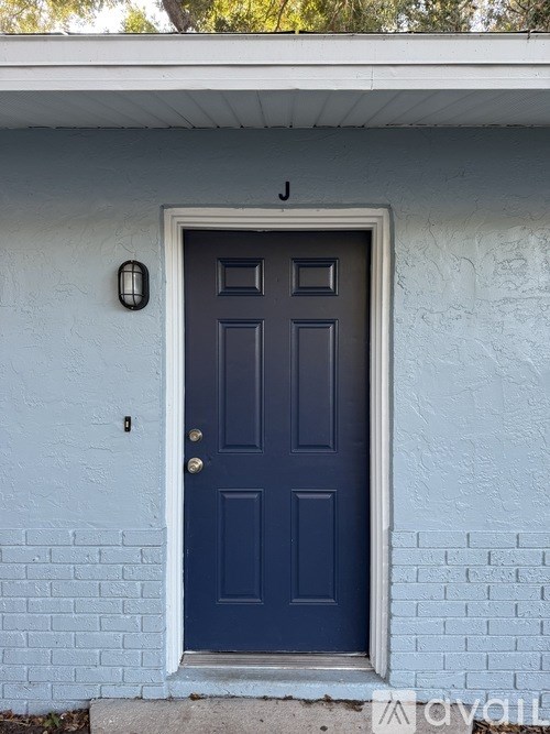 A blue door with a white frame and a black letter above it.