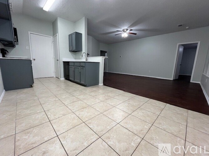 A spacious room with tile flooring and a kitchenette.