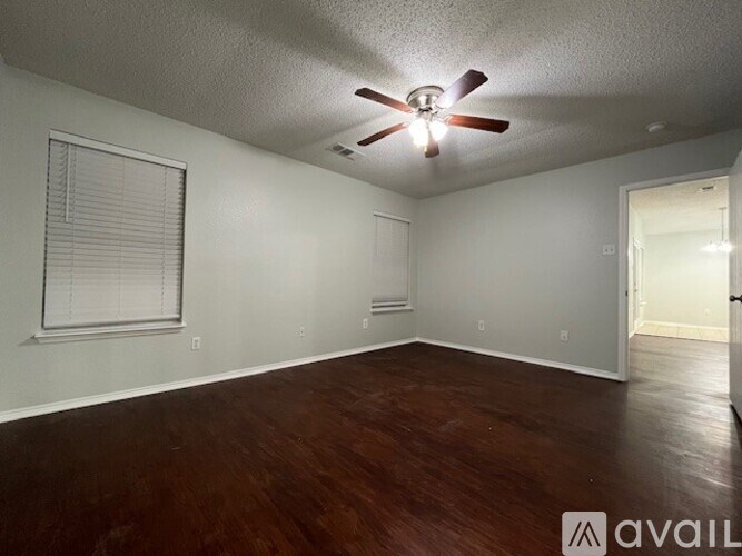 A room with a ceiling fan and wooden flooring.