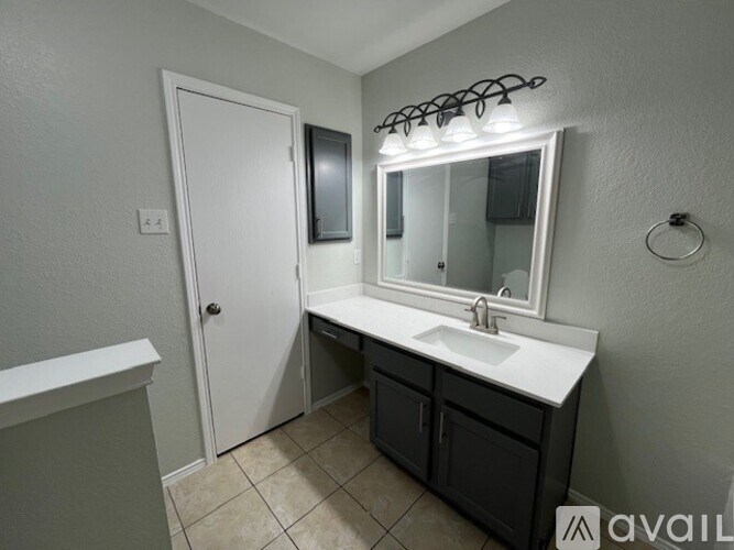 A bathroom with a white sink and a mirror with lights above it.