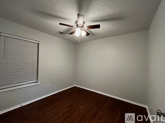A room with a ceiling fan and wooden flooring.