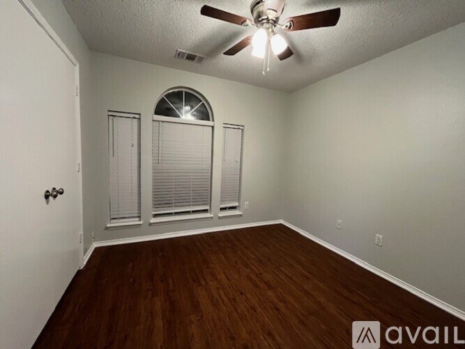 A room with a ceiling fan and wooden flooring.